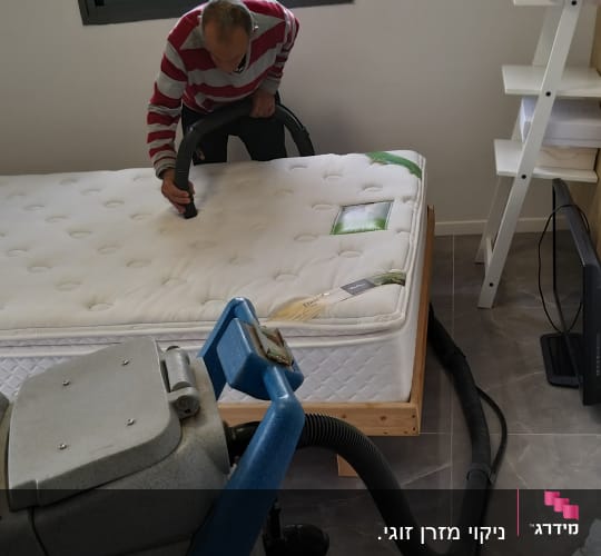 אדם מנקה מזרן עם שואב אבק תעשייתי